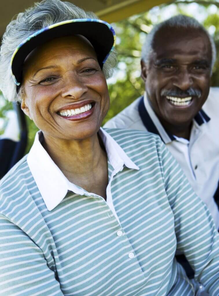 Senior couple wearing golf clothes smile to the camera.